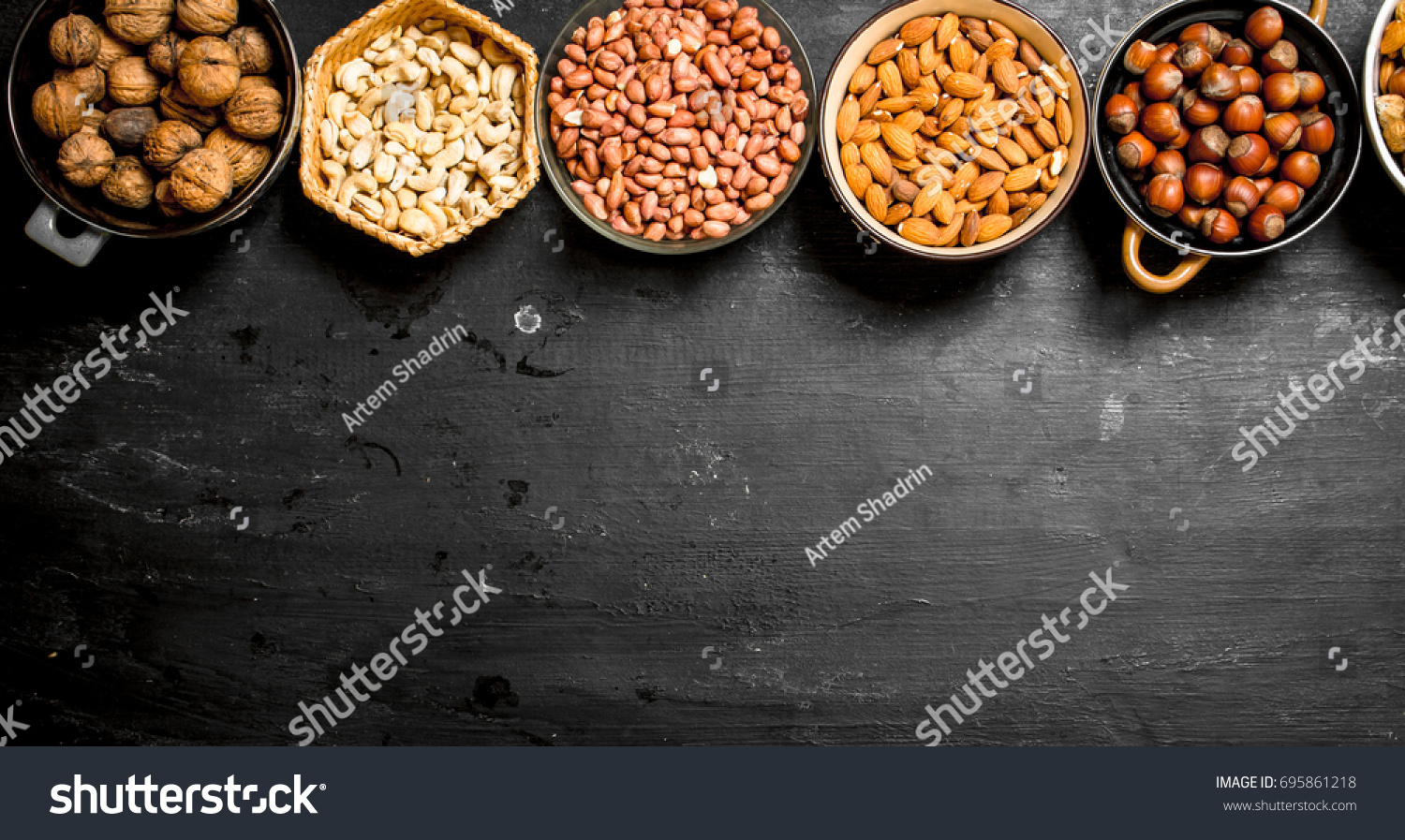 Various nuts in bowls. On a black chalkboard. #695861218