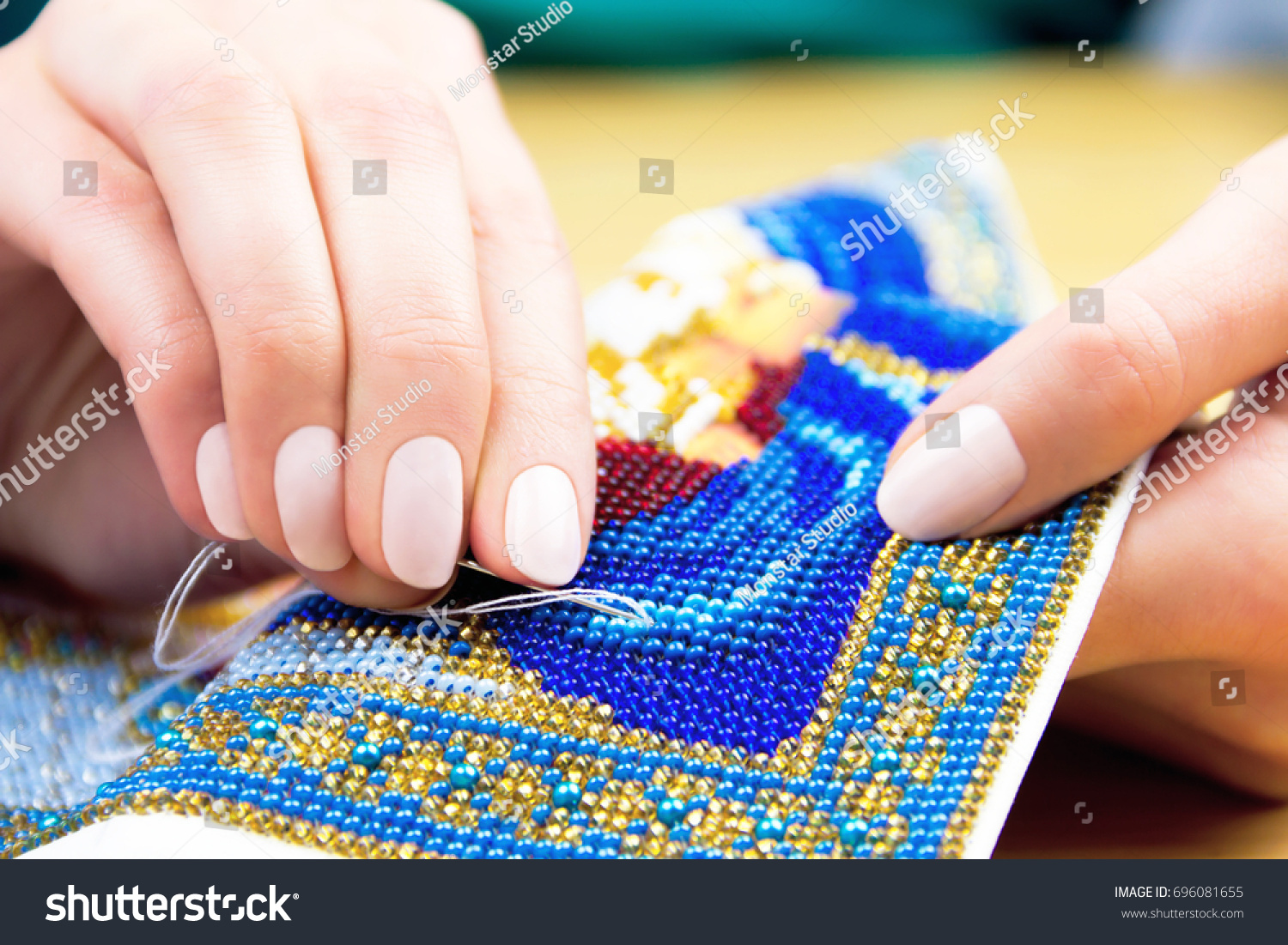 Hands of woman / female / girl bead embroidery ornament towel on wooden background #696081655