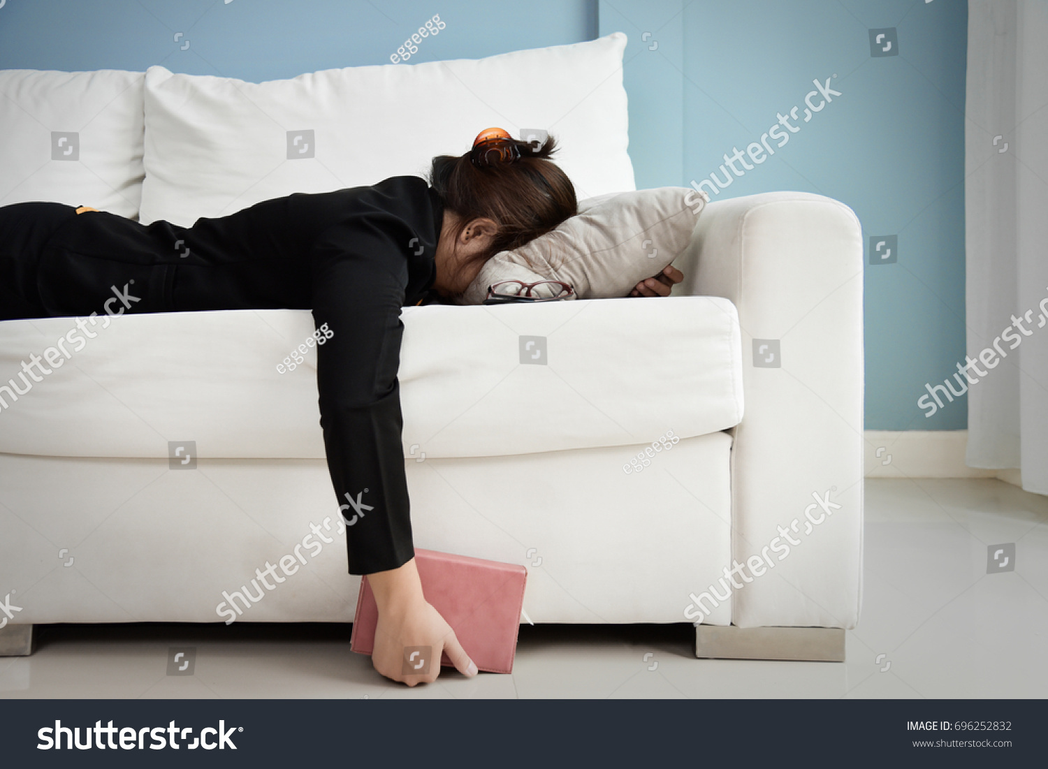Exhausted, Tired, Lazy, sleepy Asian Business woman in black suit lying on white sofa with blue wall and copy space. Stress from overtime working concept. #696252832