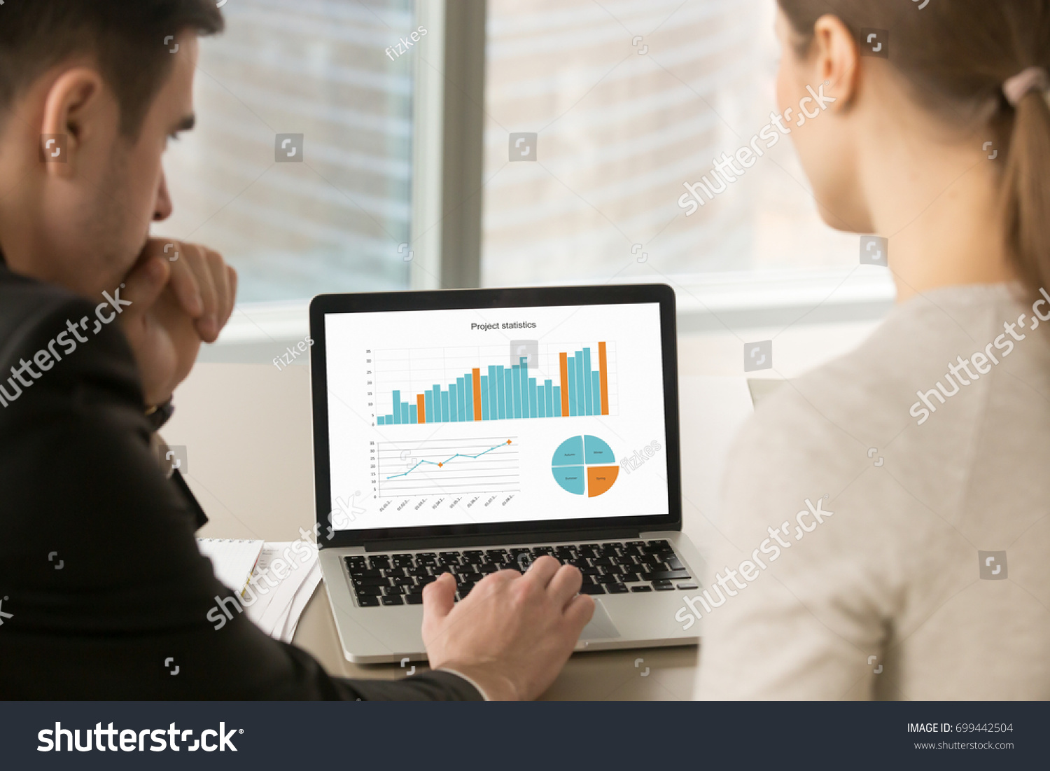 Businessman and businesswoman analyzing project statistics data on laptop screen, partners discussing infographic information about company growth, annual report analysis, close up rear view #699442504