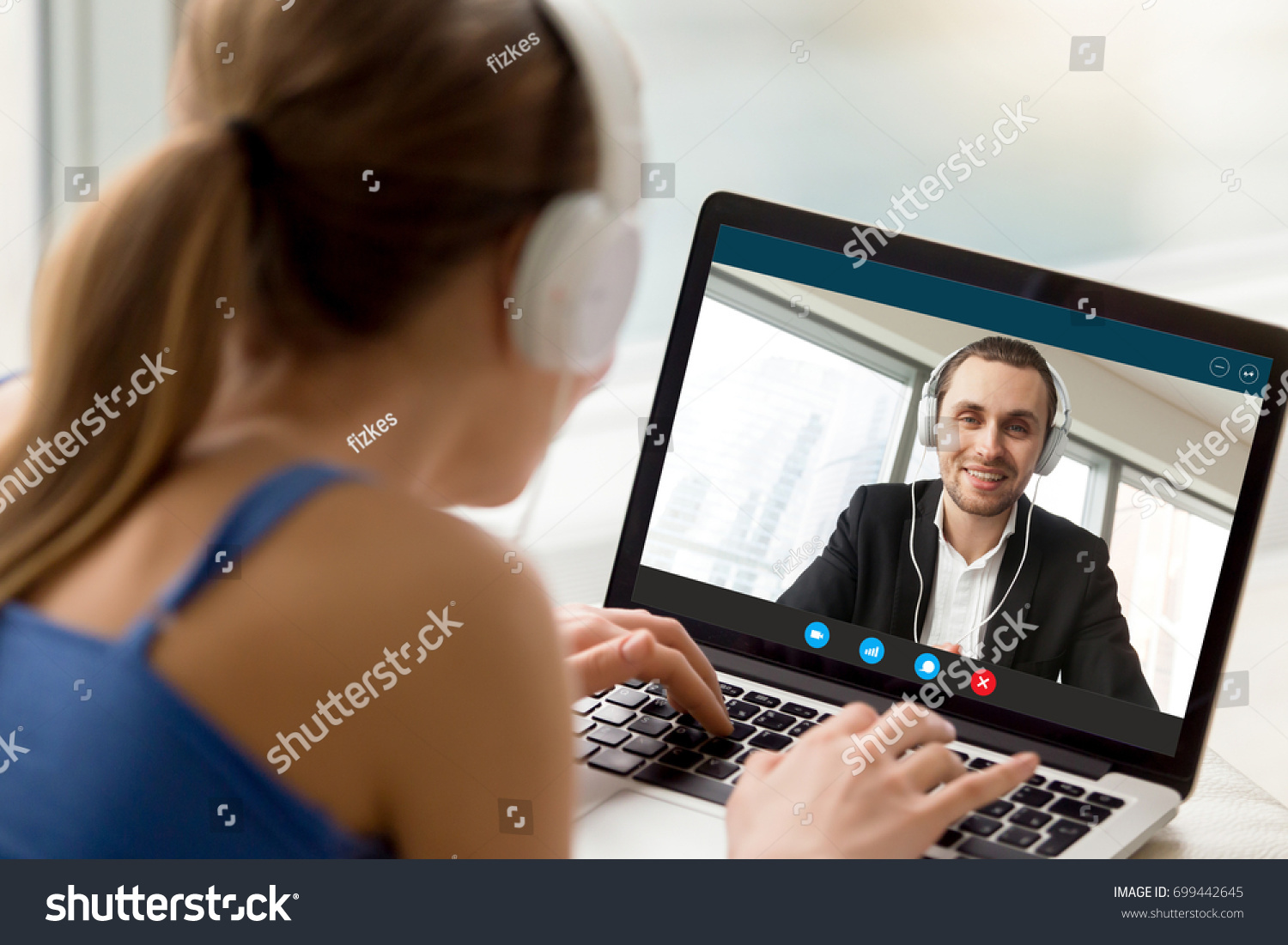 Man and woman in headphones communicating online by video call, looking at full screen videoconferencing app window, webcam videochat, virtual dating, long distance relationships, close up rear view #699442645