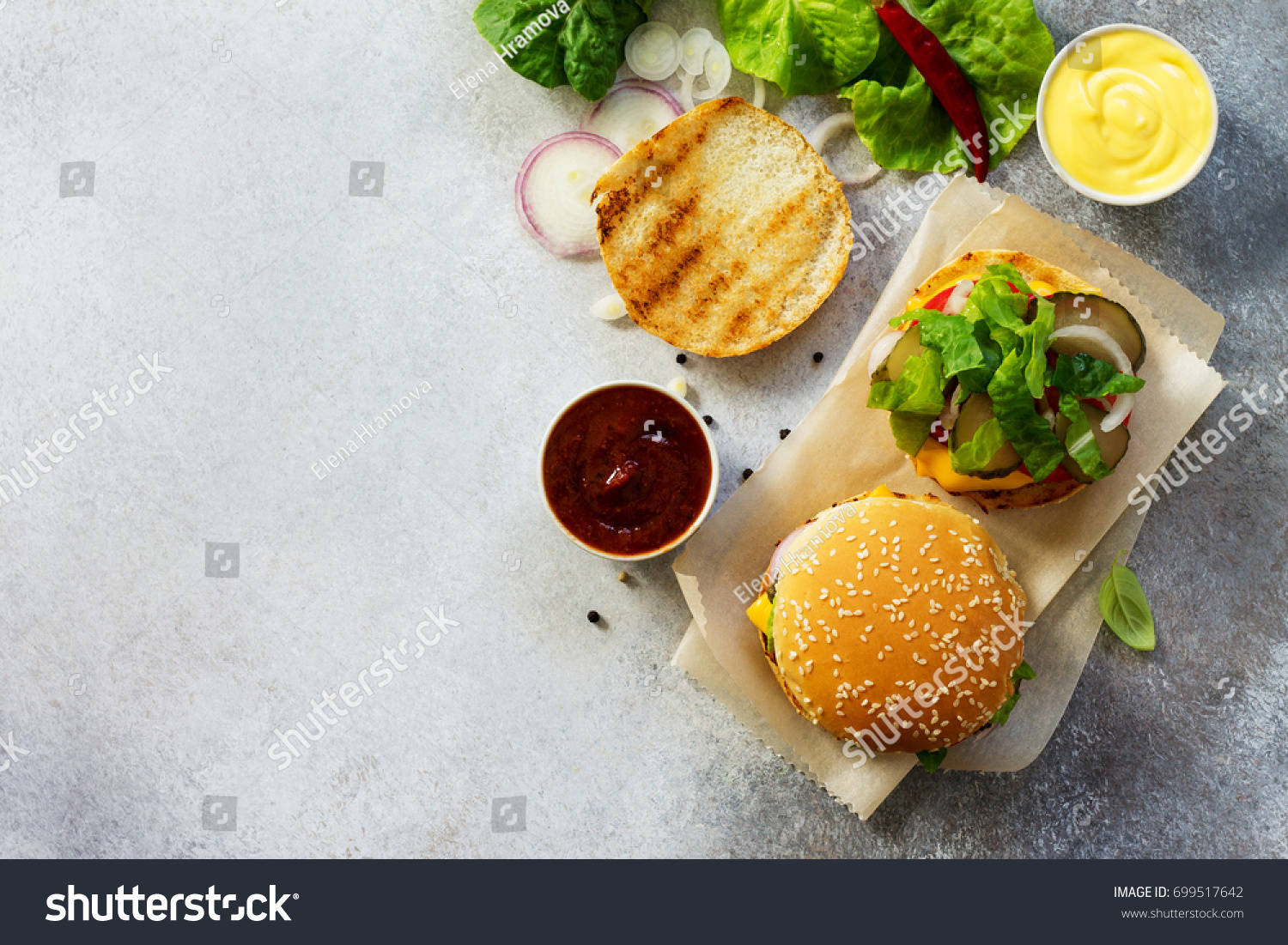 A delicious fresh homemade hamburger on a slate or stone table. Cheeseburger with meatball and vegetables. Street food, fast food. Top view with copy space. #699517642