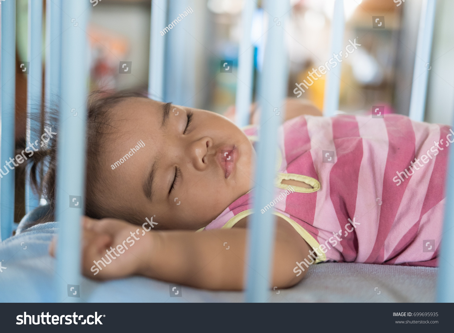 Baby girl is sleeping in baby cot. #699695935