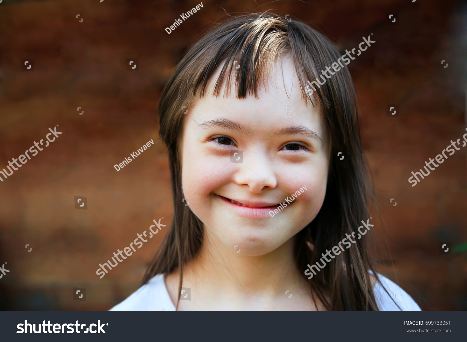 Cute smiling down syndrome girl on the brown background #699733051