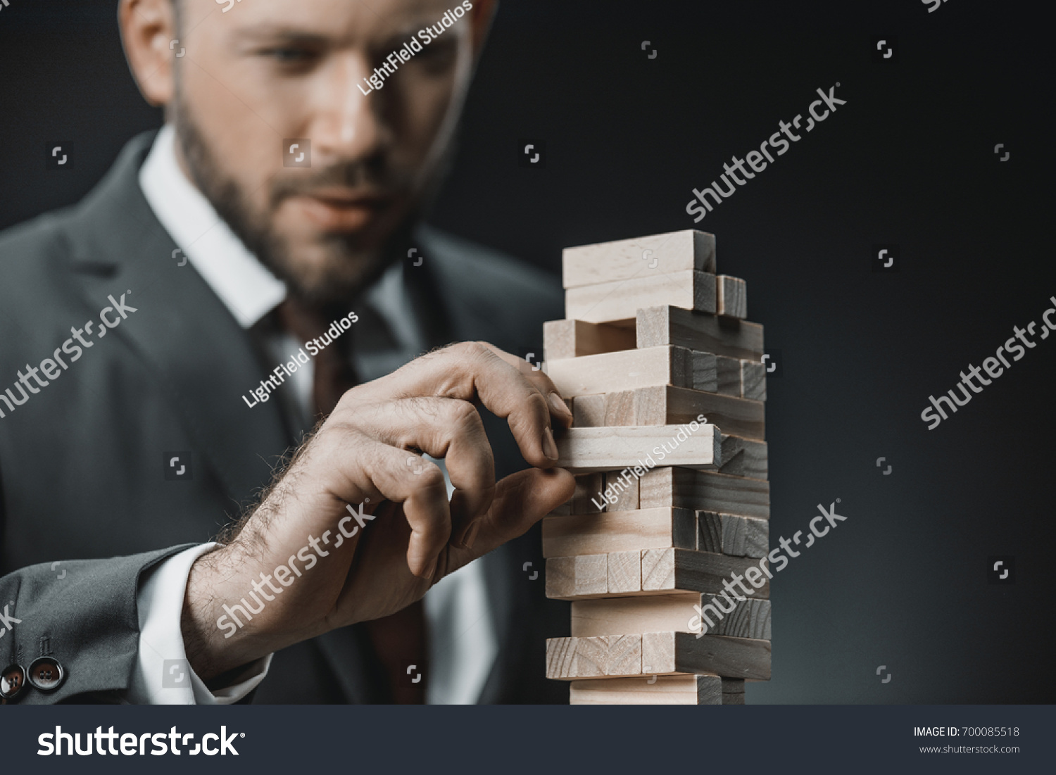 selective focus of focused businessman playing blocks wood game isolated on black #700085518