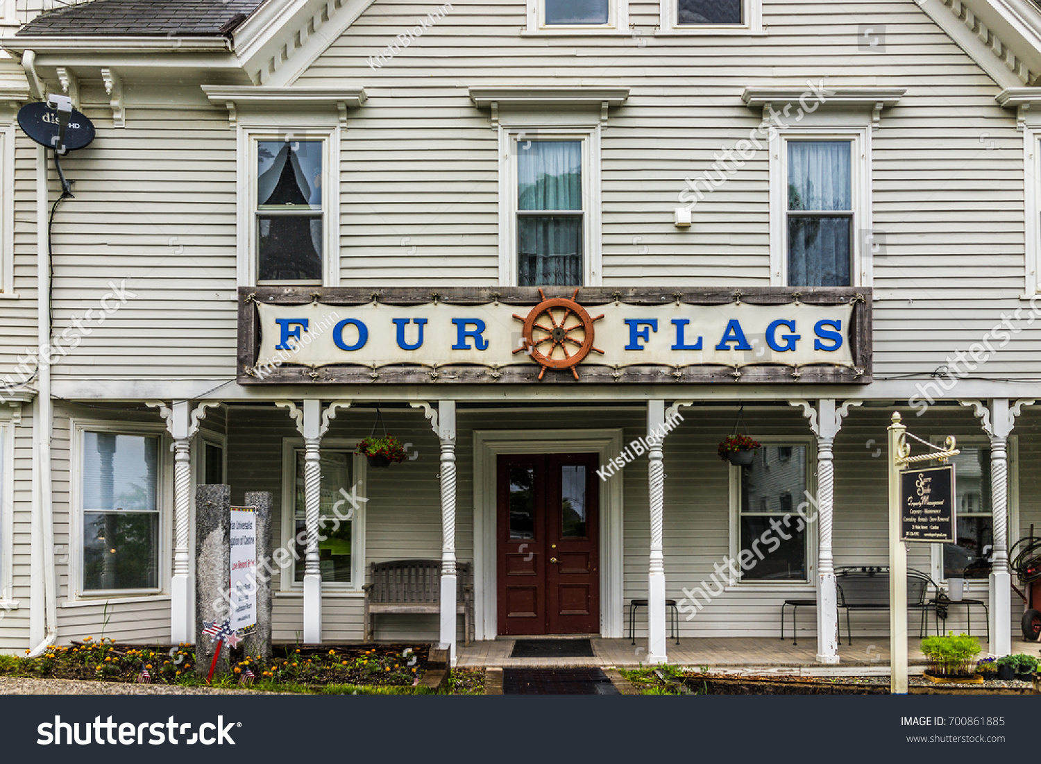 Castine, USA - June 9, 2017: Empty small village in Maine during rain with Four Flags gift shop sign with ship steering helm #700861885