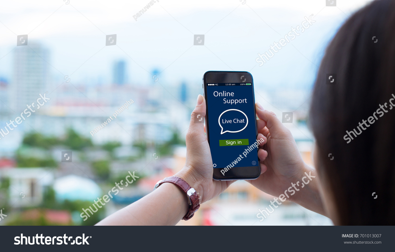 Online Live chat support concept.close-up of female hands holding mobile phone on blurred urban city as background #701013007