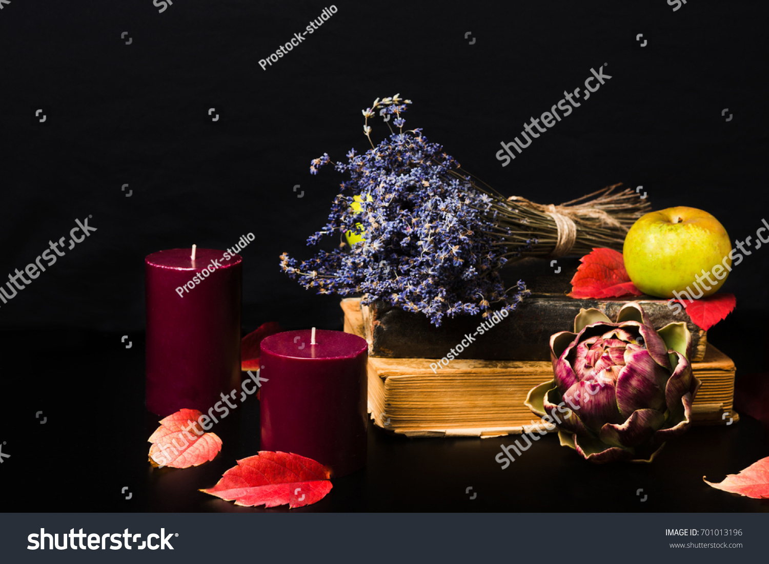 Warm fall composition on black background. Old books, candles, green apples, dry lavender, artishok and red autumn leaves making cozy romantic atmosphere. Copy space #701013196