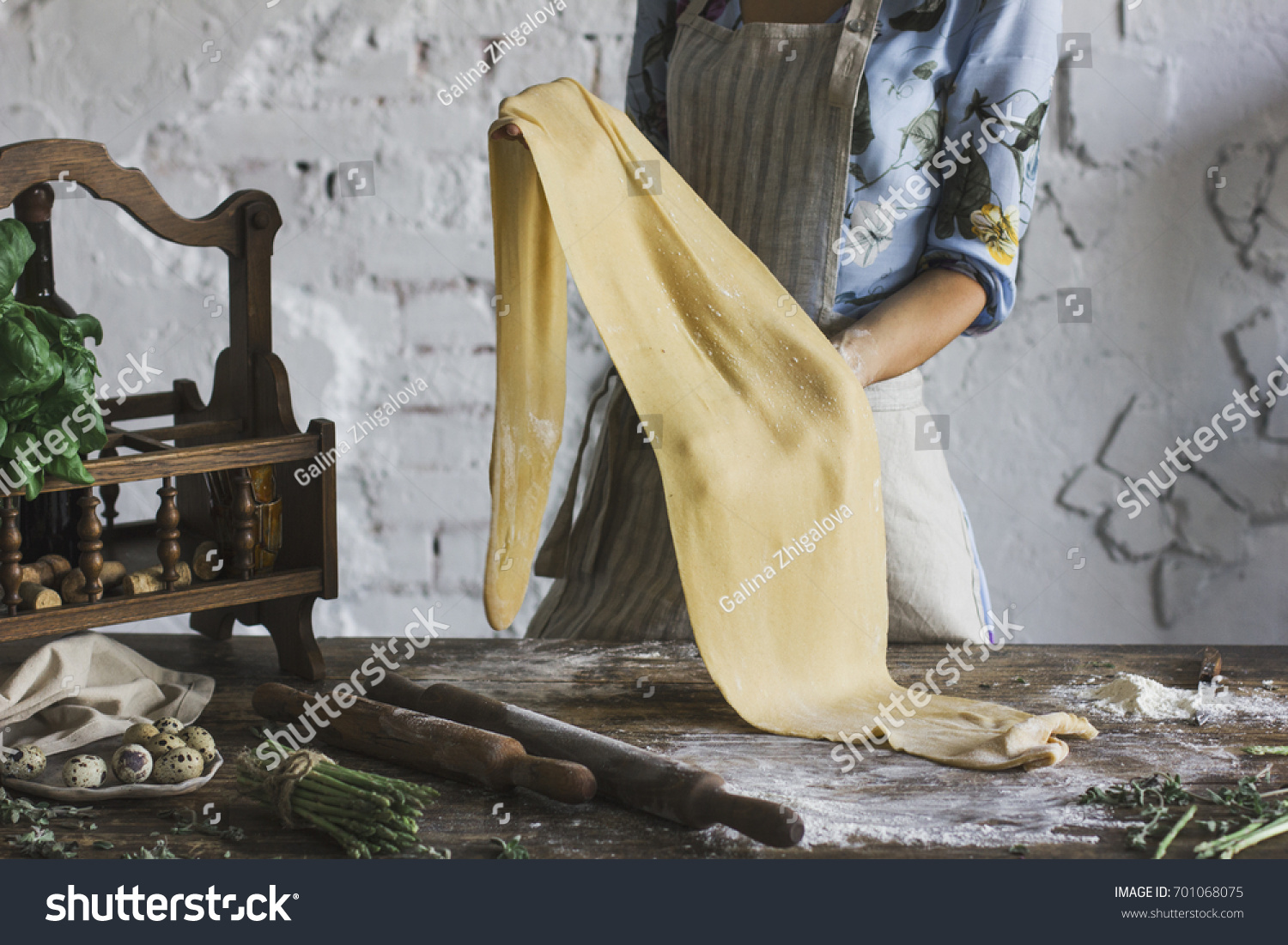 Young woman in beautiful dress and apron preparing the dough for homemade pasta #701068075