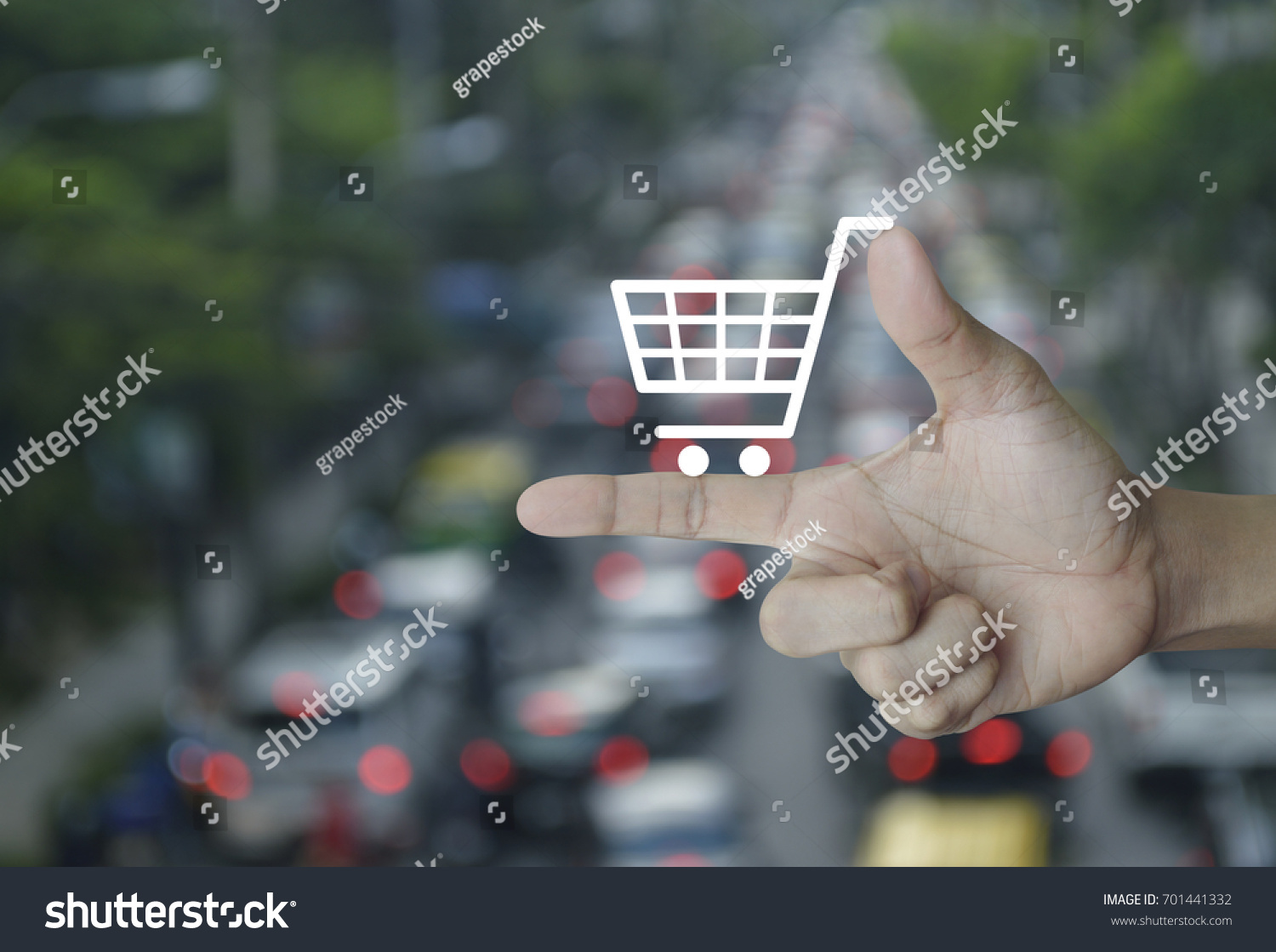 Shopping cart icon on finger over blur of rush hour with cars and road, Shop online concept #701441332