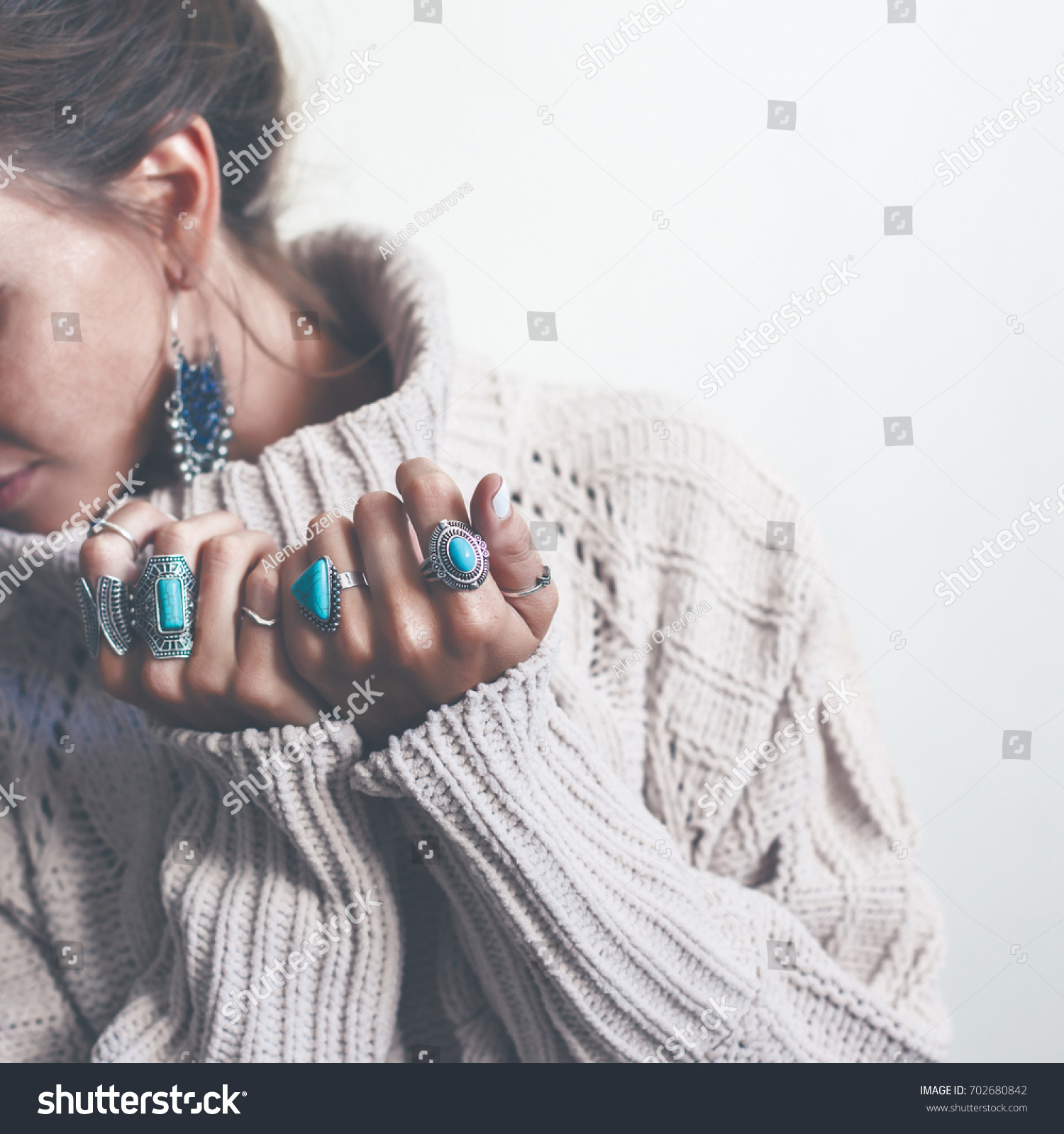 Boho jewelry on model: ethnic stone rings and earrings. Beautiful woman wearing warm woolen sweater and fashion jewellery. Minimal style and pastel tone. #702680842