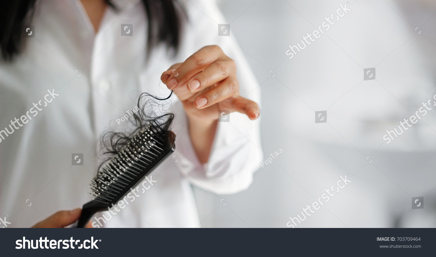 woman losing hair on hairbrush in hand, soft focus #703709464