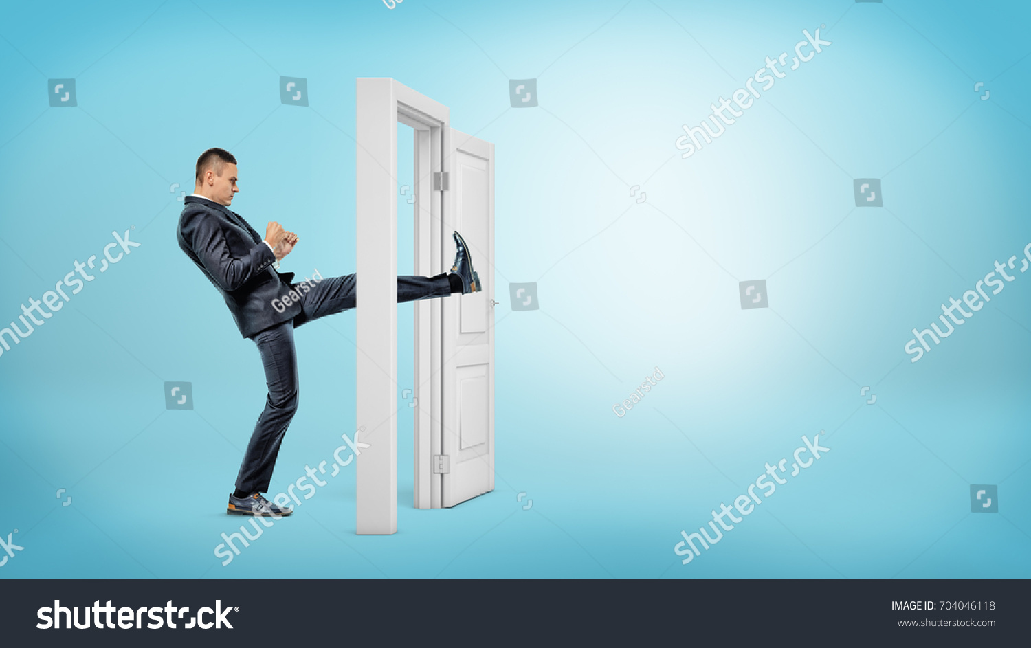 A businessman in side view kicks a small white door open with his leg on blue backgrounds. Business and success. Opening all doors. Aggressive business approach. #704046118