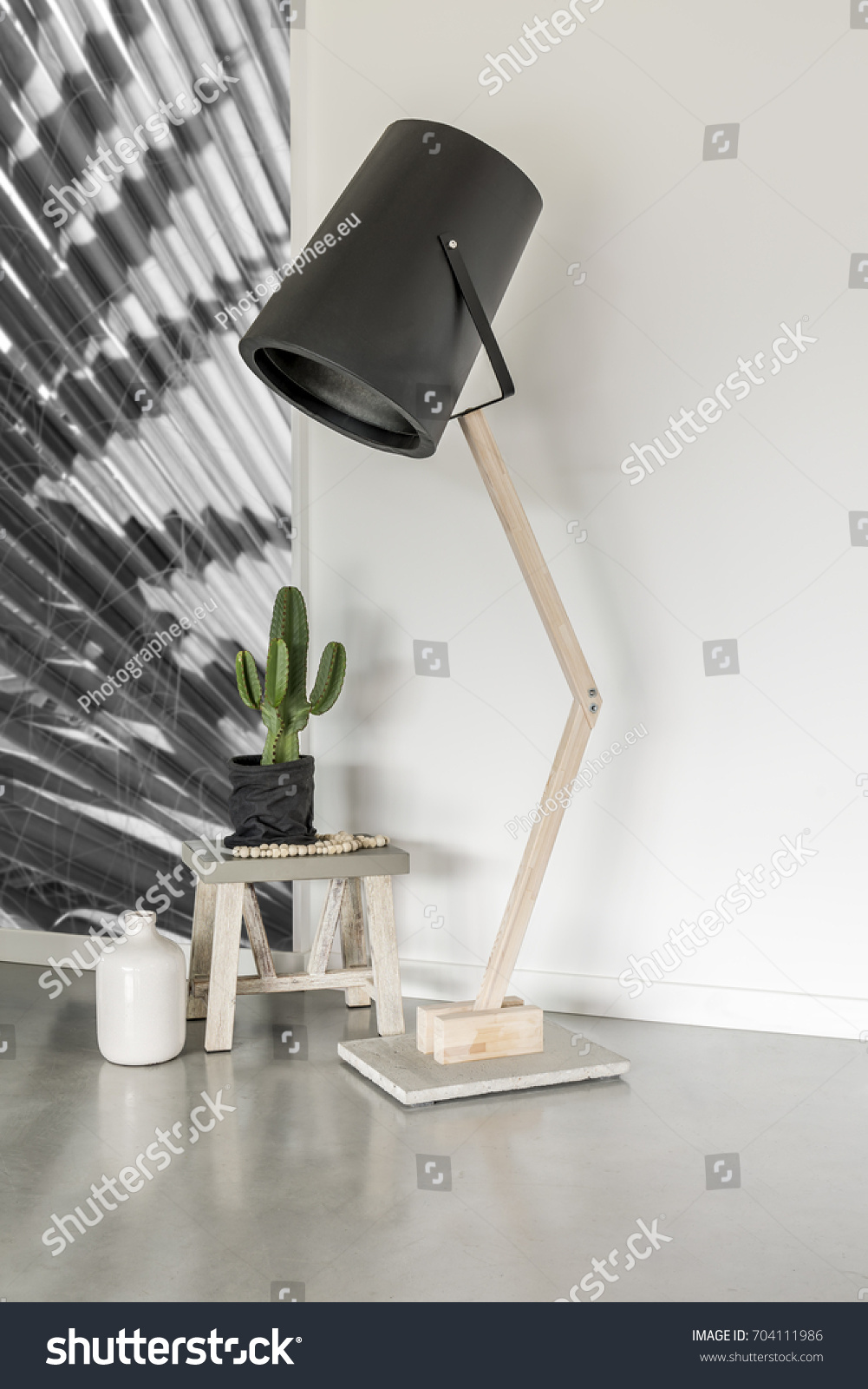 Modern lamp in a minimalist room with a cactus on a stool #704111986