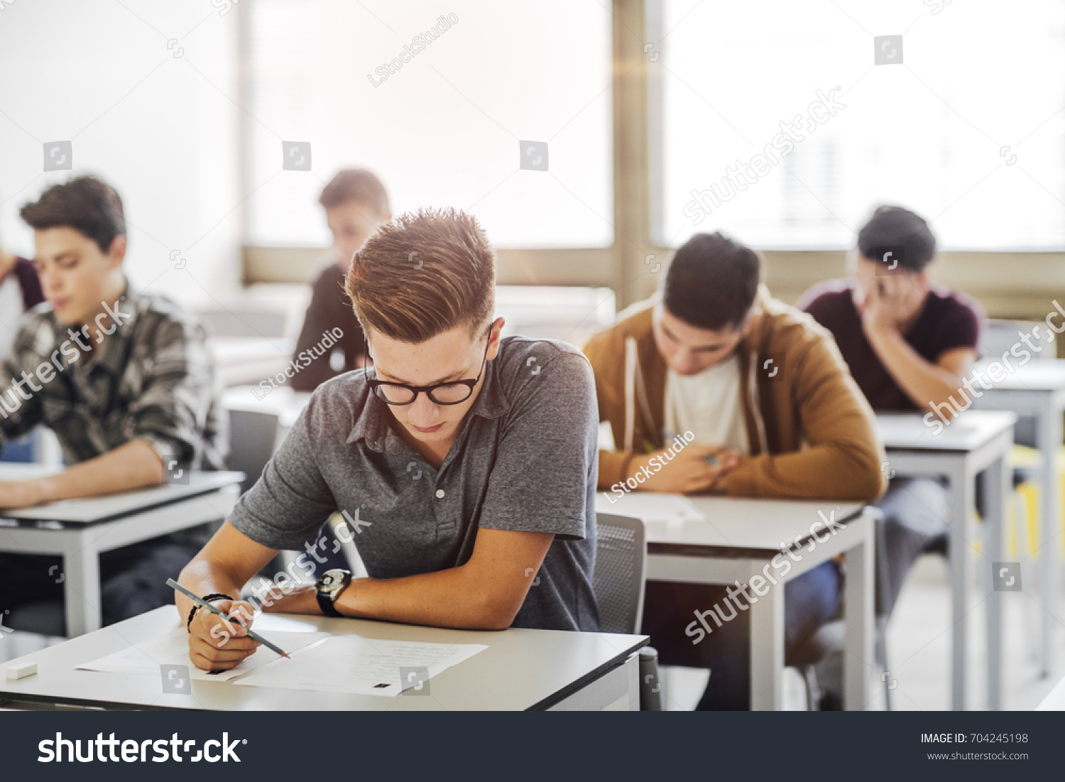 Group of high school students doing exam at classroom. #704245198
