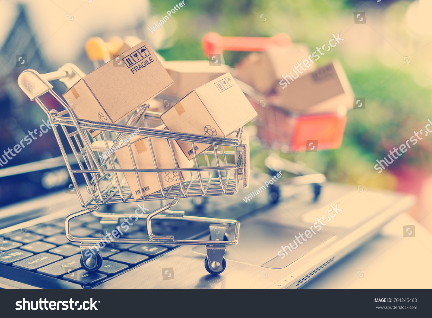 Freight or shipping service for online shopping or ecommerce concept : Paper boxes or cartons in metal shopping cart on a computer laptop keyboard. Customer always buy things via internet worldwide. #704245480
