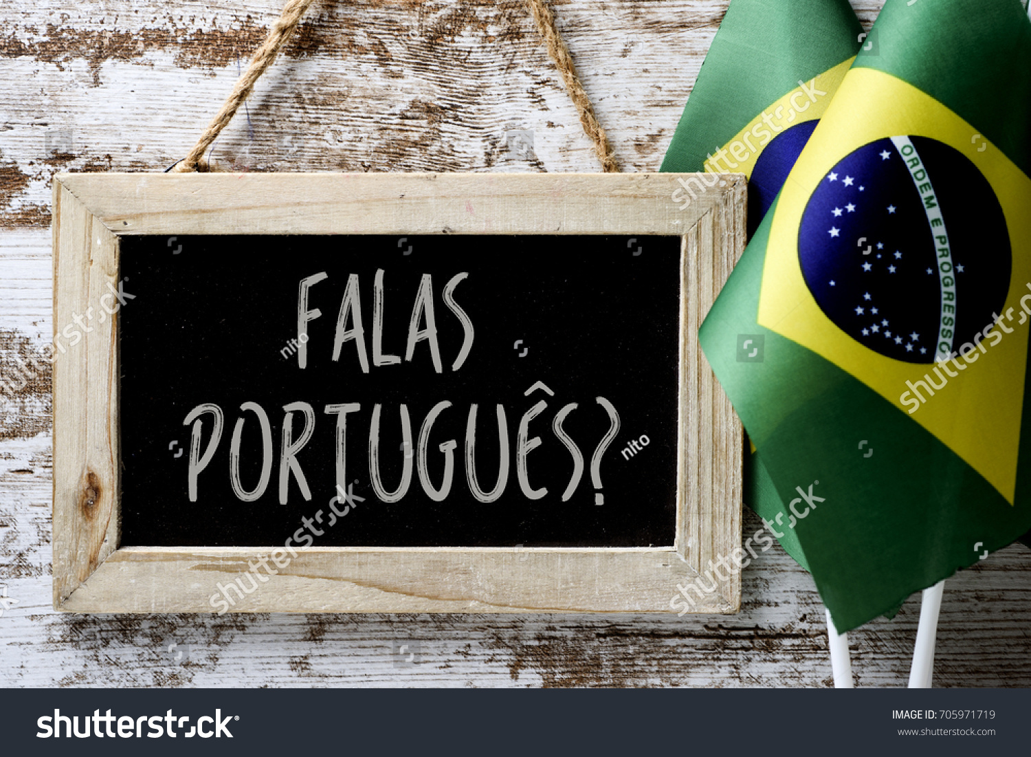 a wooden-framed chalkboard with the question falas portuges? do you speak Portuguese? written in Portugese, and some flags of Brazil against a rustic wooden background #705971719