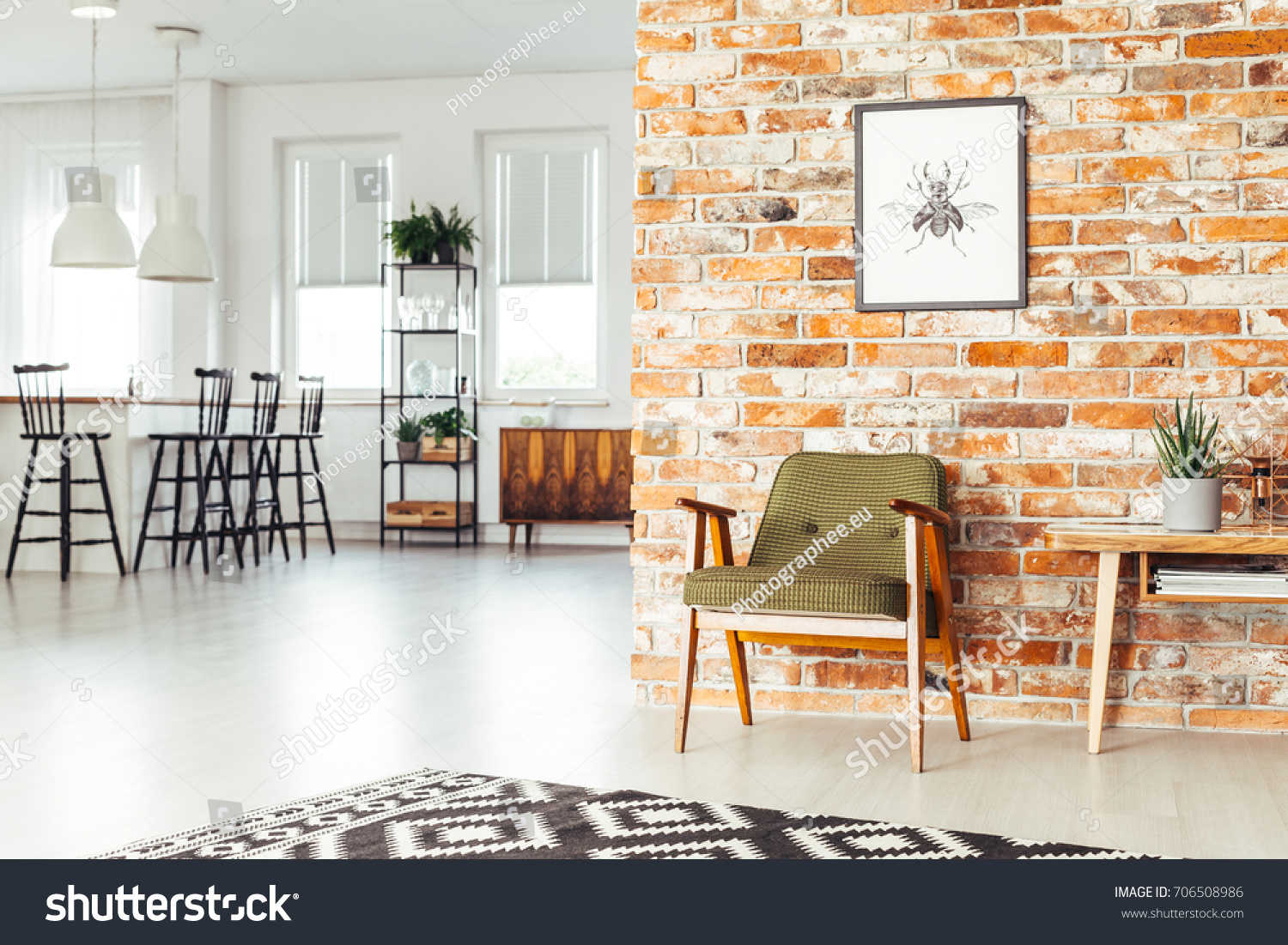 White lamps above countertop with bar stools in dining room with rustic furniture and poster on brick wall #706508986