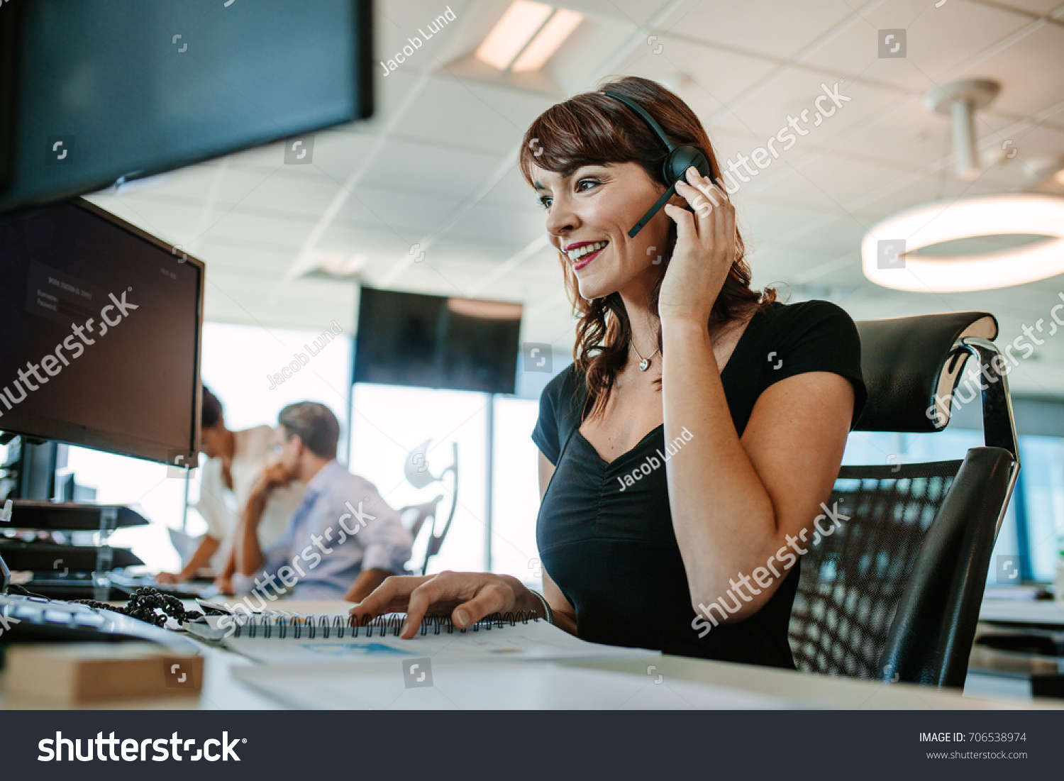 Call center business woman talking on headset. Caucasian female in customer service position talking on the phone. #706538974