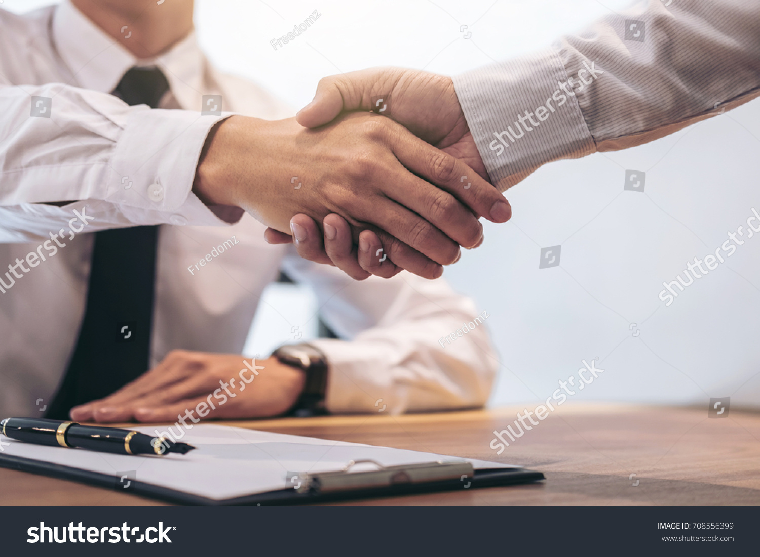 Real estate broker agent and customer shaking hands after signing contract documents for realty purchase, Bank employees congratulate, Concept mortgage loan approval. #708556399