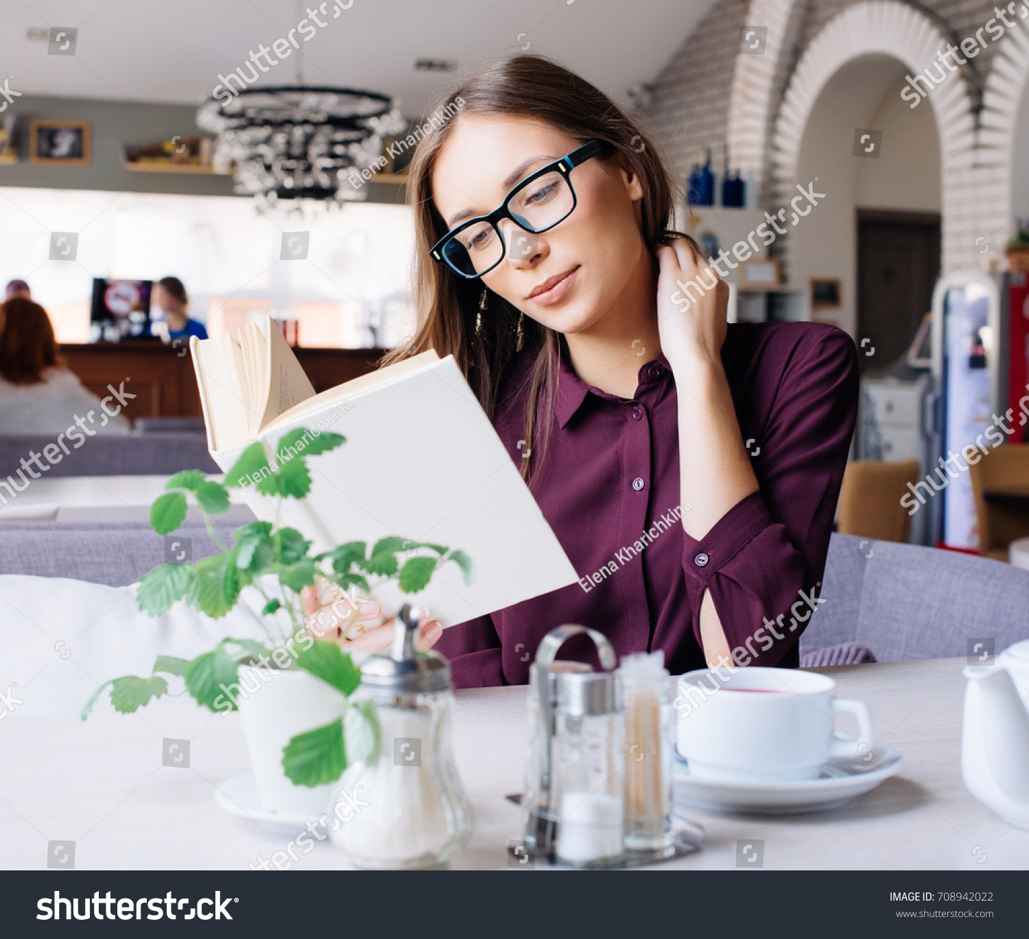 Concentrated at work. Confident young woman in smart casual wear working on laptop while sitting near window in creative office or cafe. #708942022
