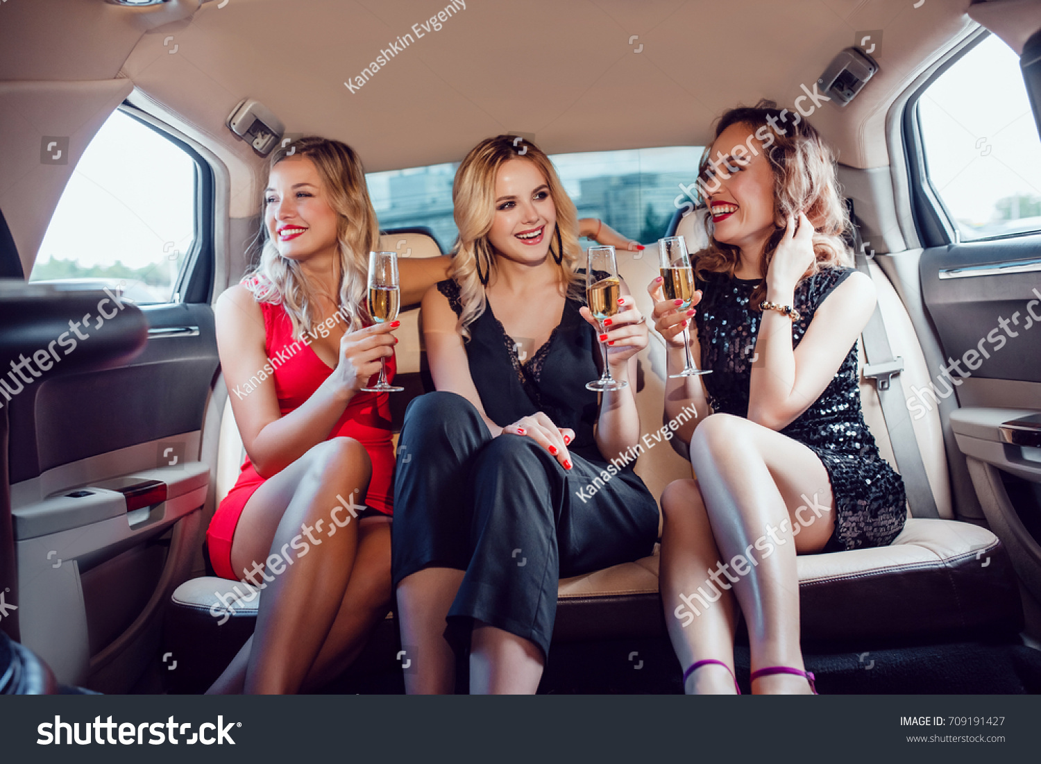 Pretty women having party in a limousine car and drinking champagne. #709191427
