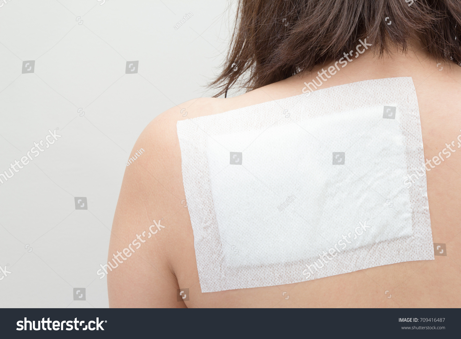 medicated pain relief patch in back of female #709416487