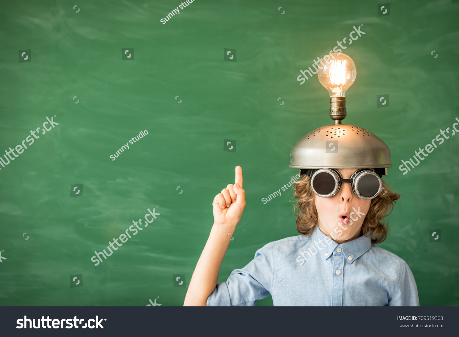 Portrait of child in classroom. Child with toy virtual reality headset in class. Success, idea and innovation technology concept. Back to school. Kid against blackboard with copy space #709519363