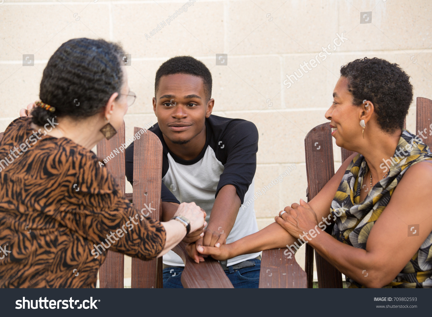 Closeup portrait, young handsome man having conversation with family sitting down, isolated outdoors background #709802593