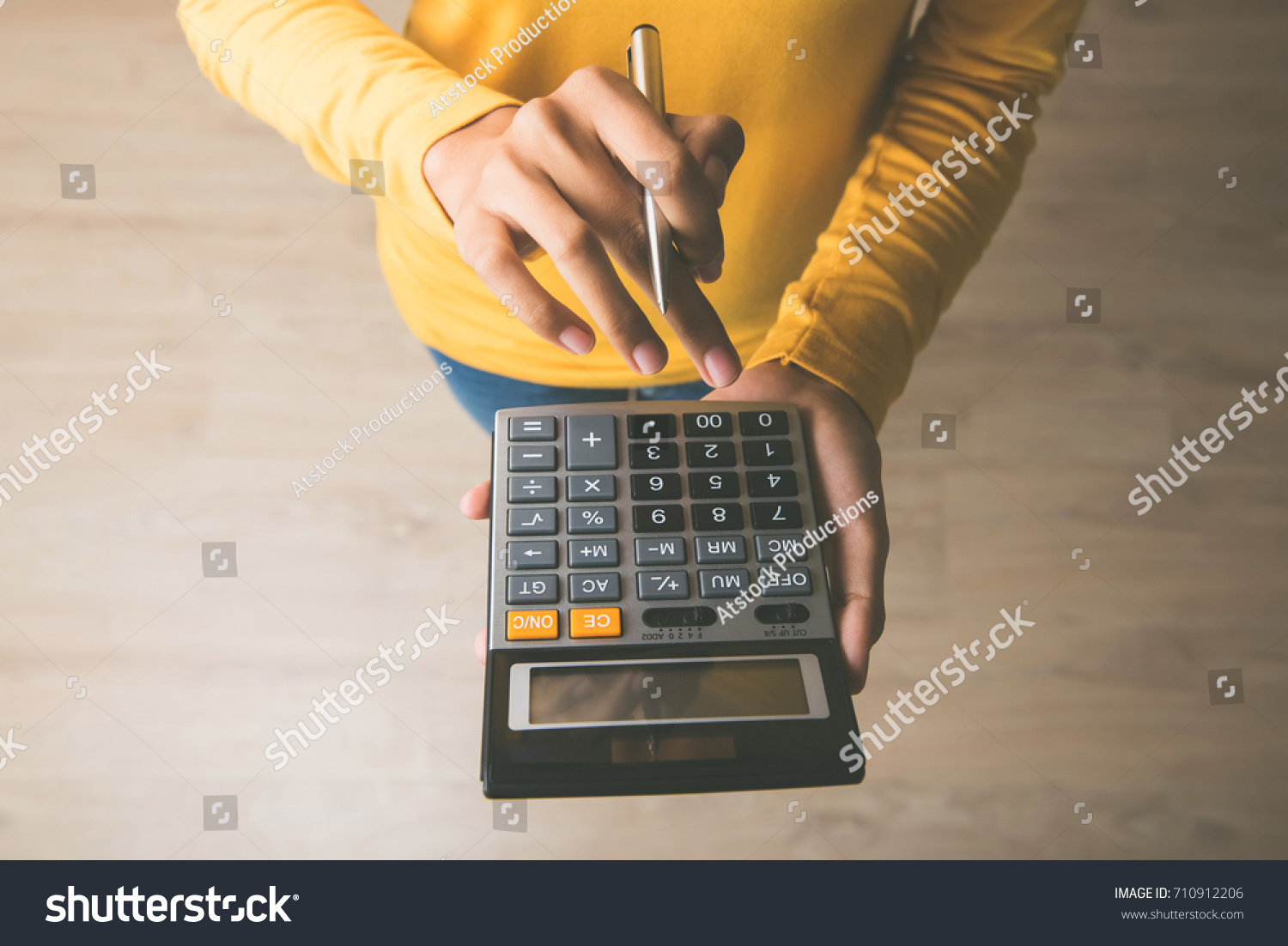 Woman entrepreneur using a calculator with a pen in her hand, calculating financial expense at home office #710912206