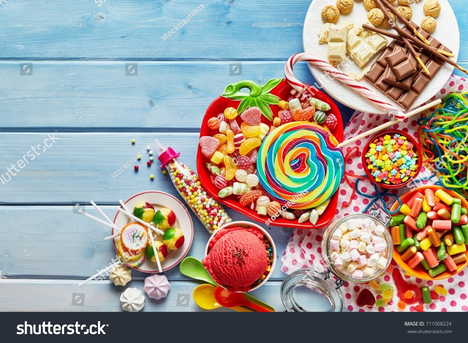 Overhead view of colorful array of different childs sweets and treats in bowls on light blue wood background #711008224
