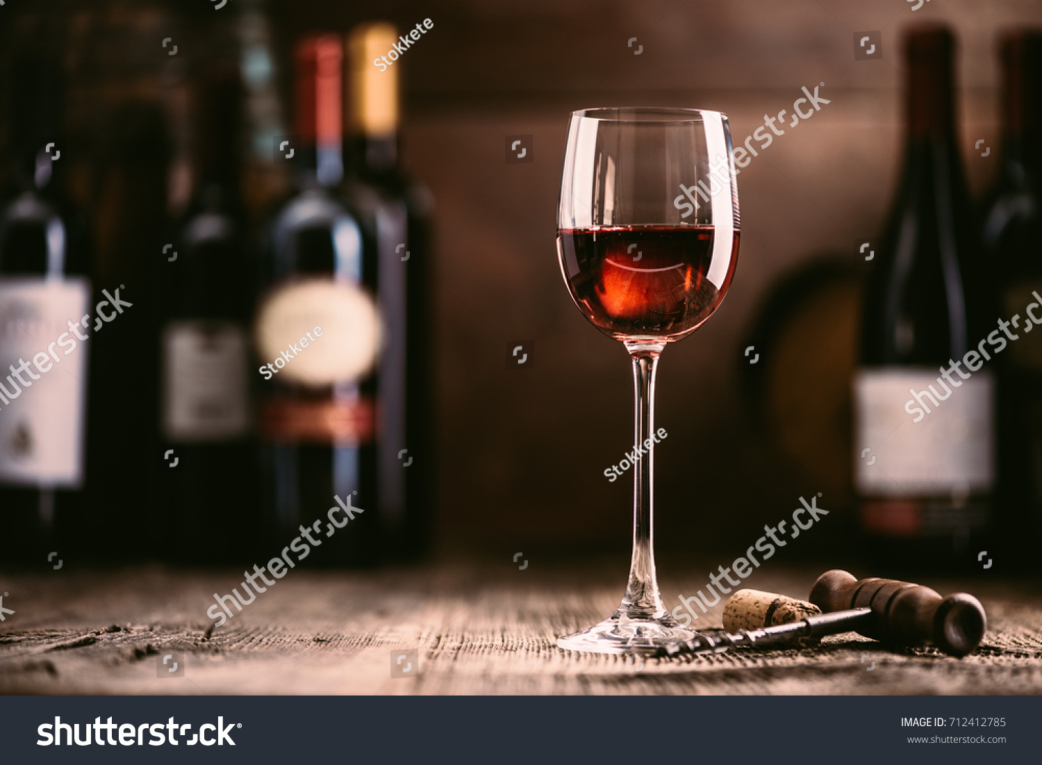 Wine tasting experience in the rustic cellar and wine bar: red wine glass and collection of excellent wines on the background #712412785