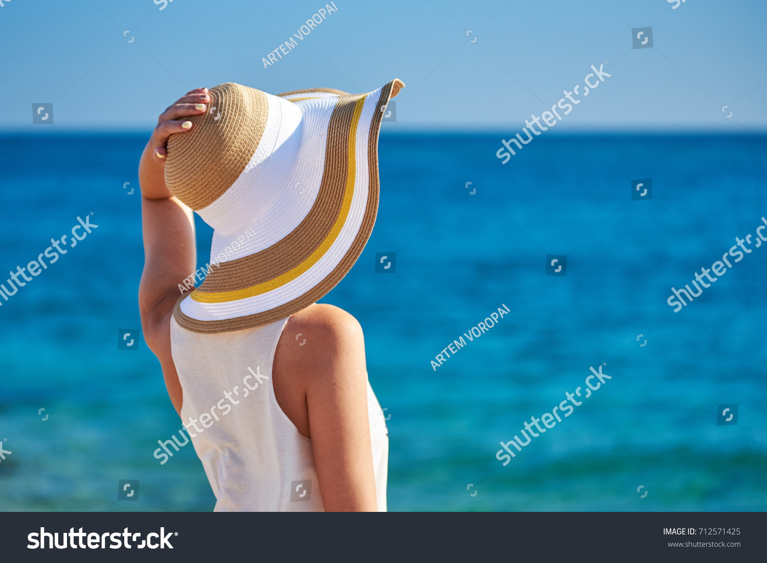 Woman in beach hat against the sea. #712571425