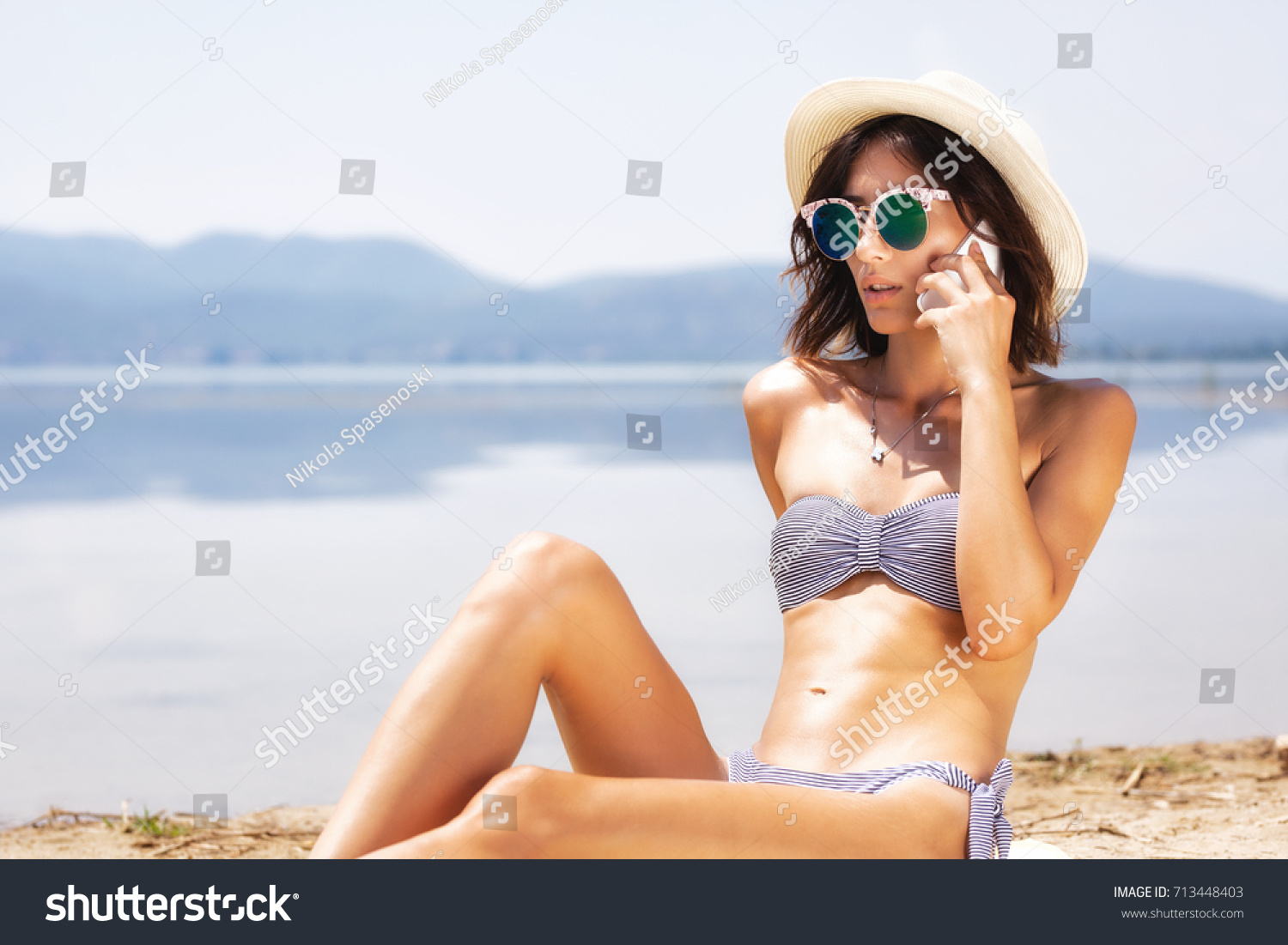 girl sunbathing and talking on a smart phone #713448403