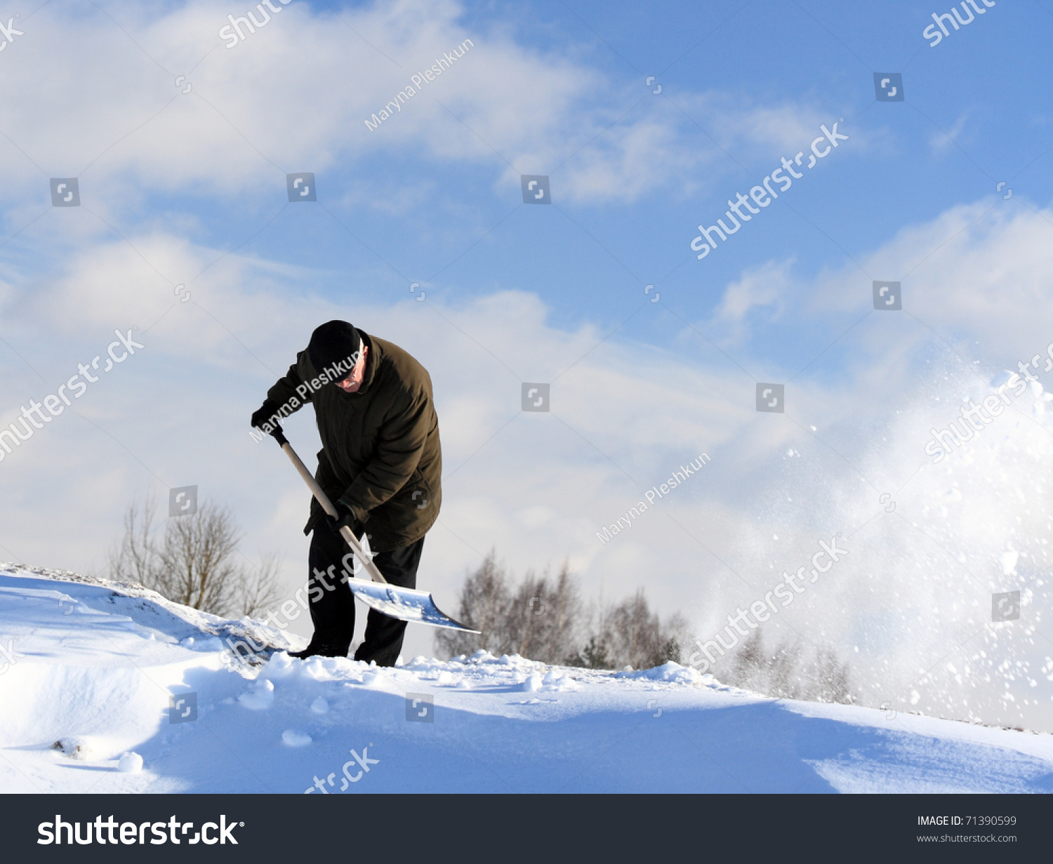 A man with a shovel removing snow from a driveway #71390599