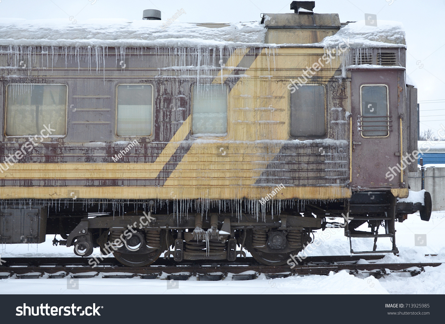 Detailed photo of a frozen car passenger train with icicles and ice on its surface. Railway in the cold winter season #713925985