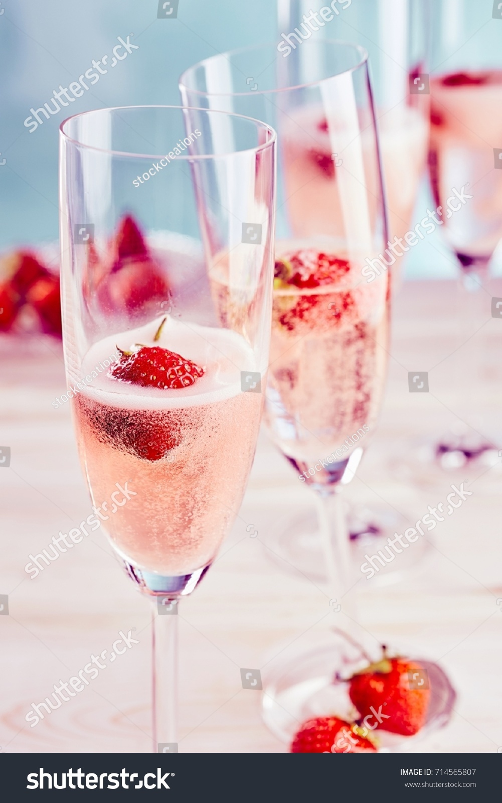 Delicious sparkling pink champagne with fresh strawberries served in stylish flutes for a romantic celebration or special occasion #714565807