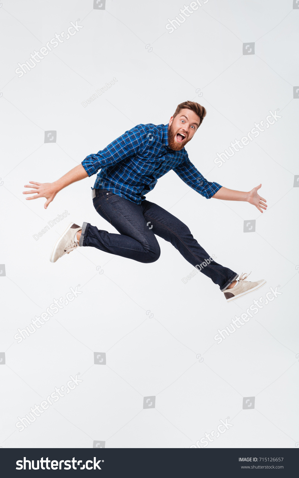 Full length portrait of a happy excited bearded man jumping and looking at camera isolated over white background #715126657