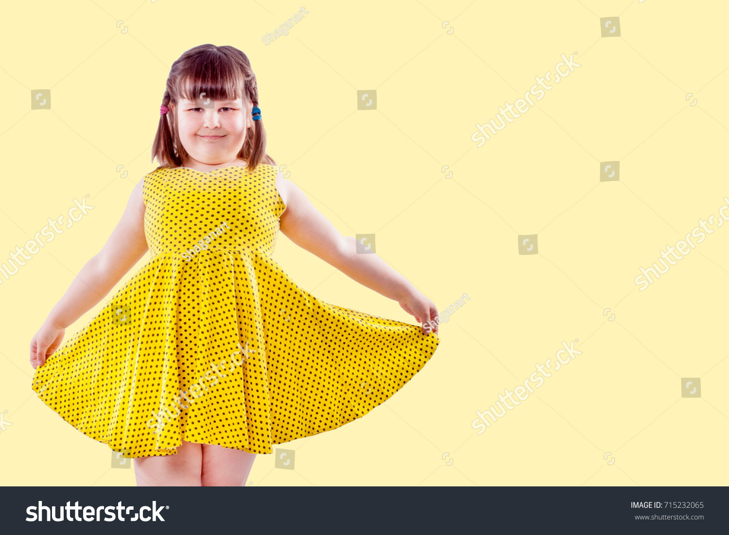 cute small girl in yellow on pale yellow background with copy space #715232065