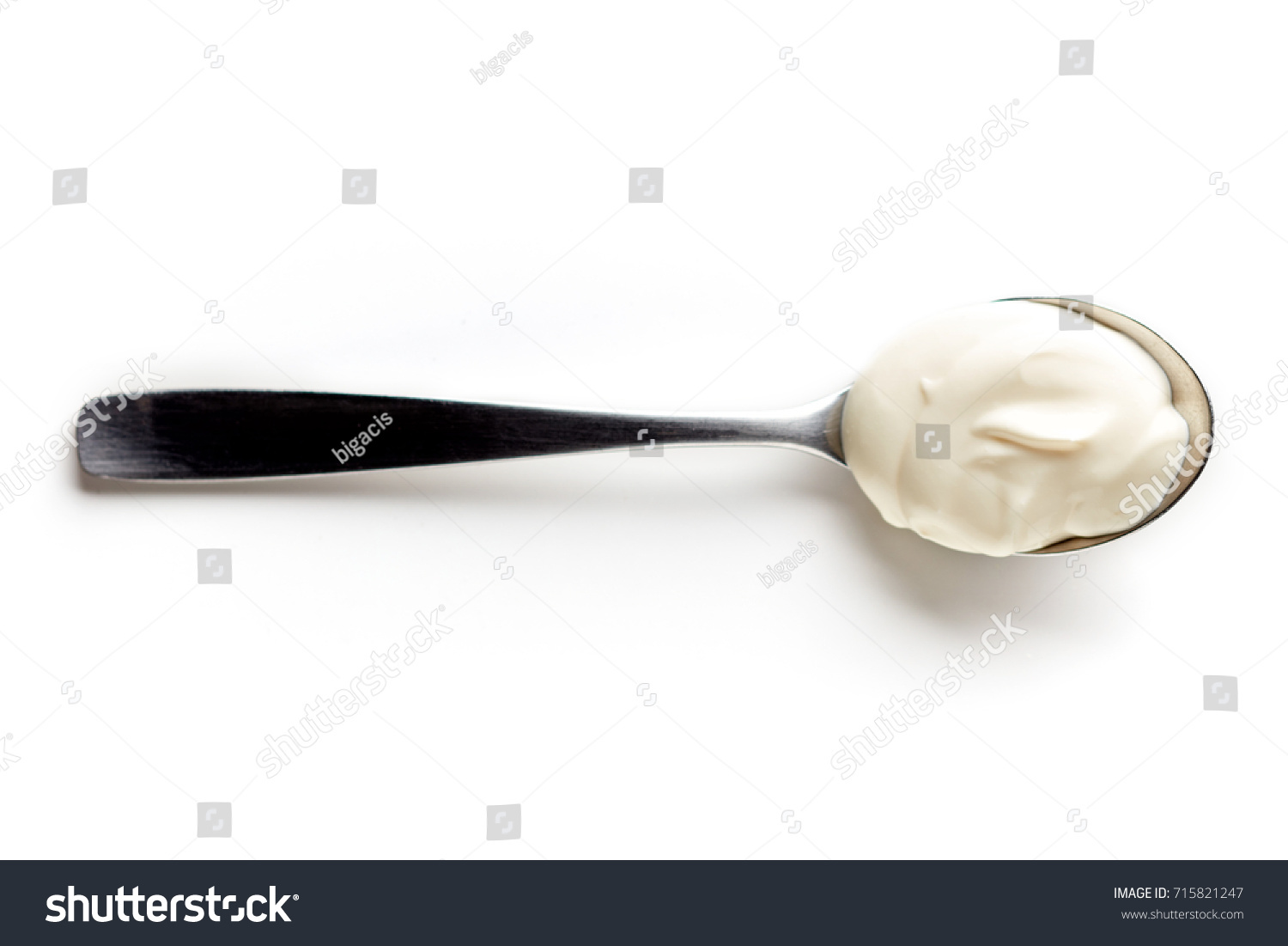 Sour cream in a spoon, isolated on white background, top view #715821247