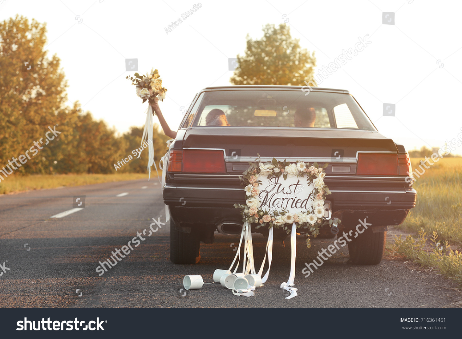 Happy wedding couple in decorated car #716361451