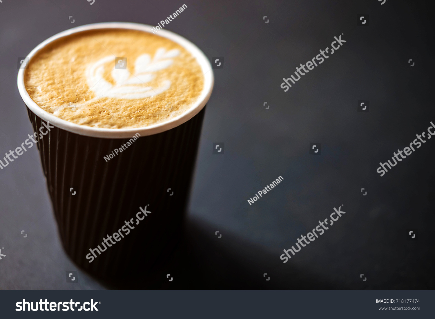 Soft focus of Latte art hot coffee in black paper cup on gray background with shadow , blurred and soft focus image #718177474