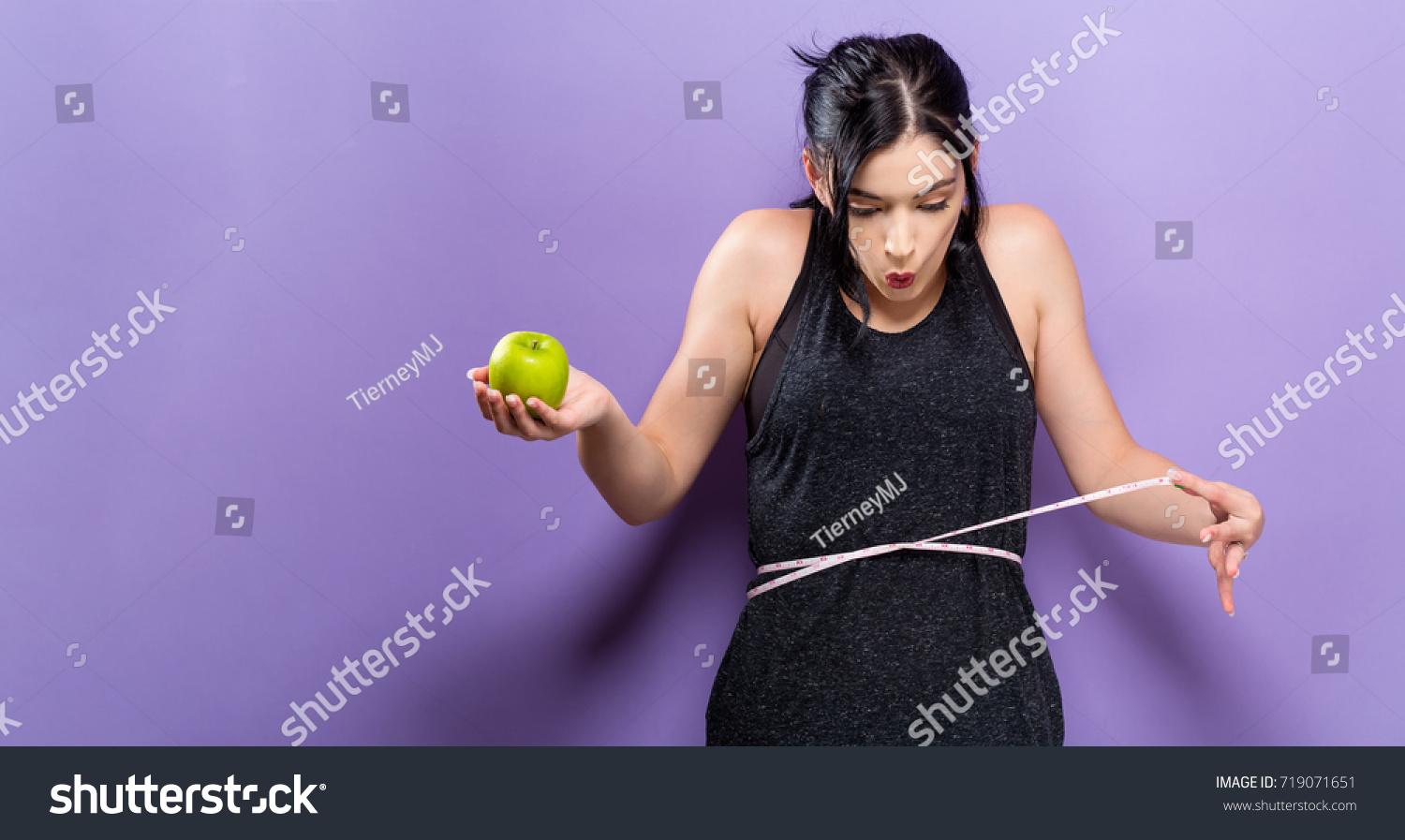 Young woman measuring her waist with a tape measure #719071651