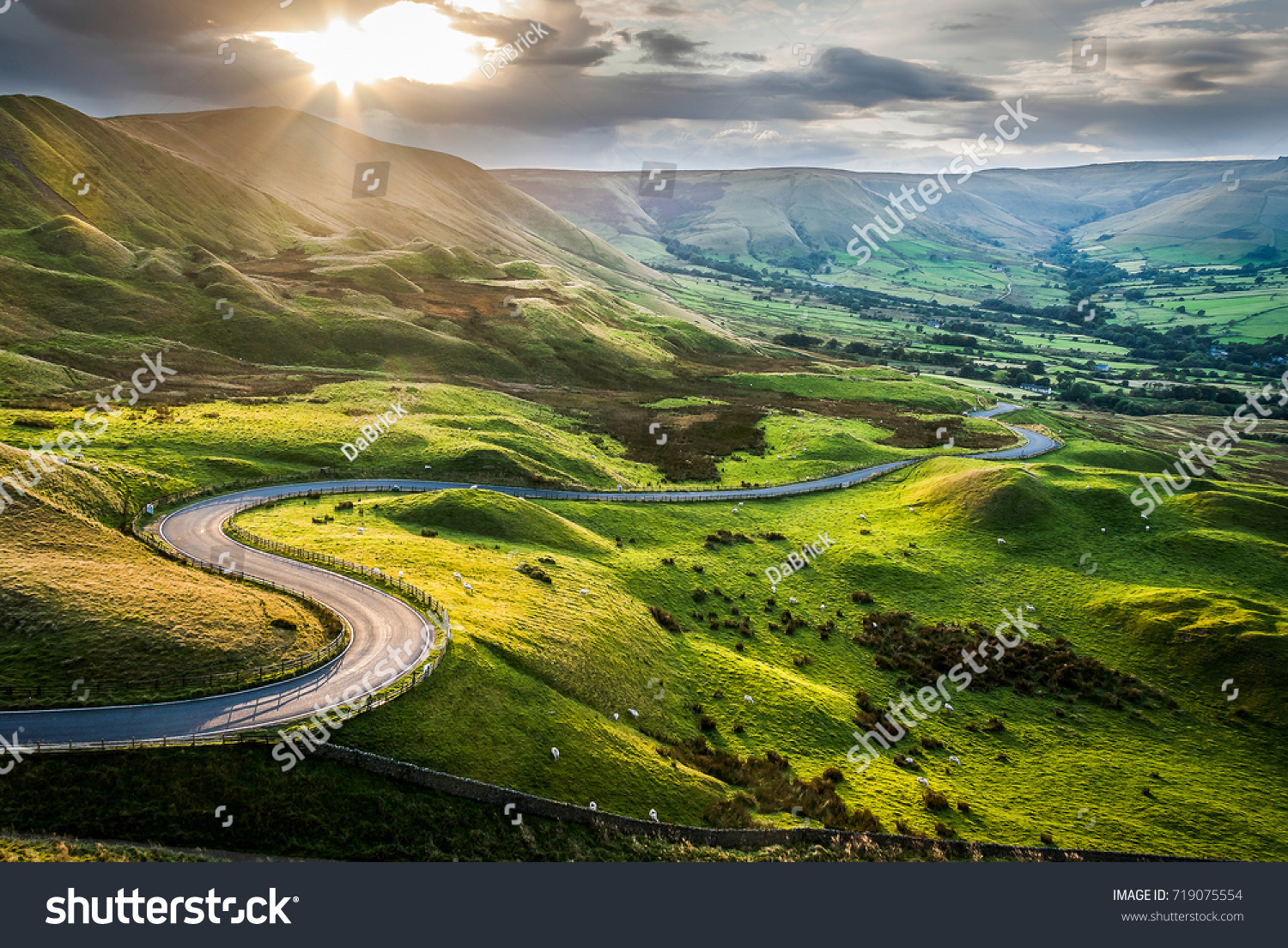 Sunset at Mam Tor, Peak District National Park, with a view along the winding road among the green hills down to Hope Valley, in Derbyshire, England. #719075554