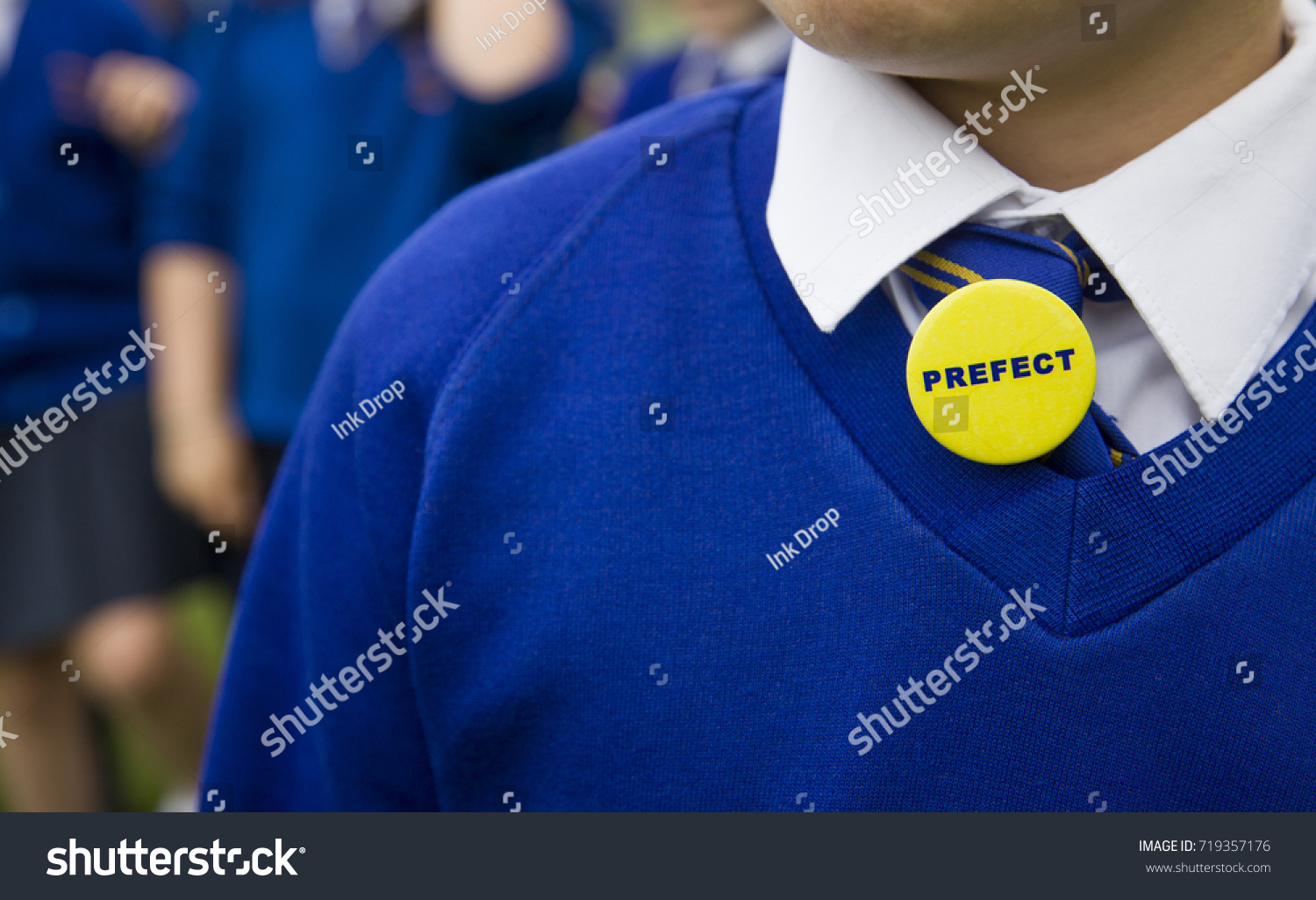 Young person in blue school uniform with a prefect badge #719357176
