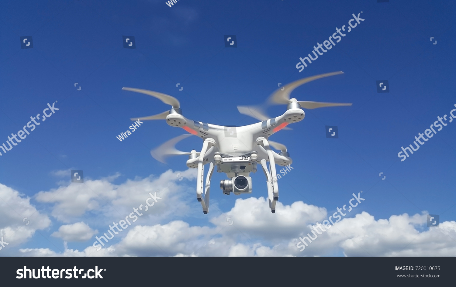 Flying drone with blue sky and clouds background #720010675