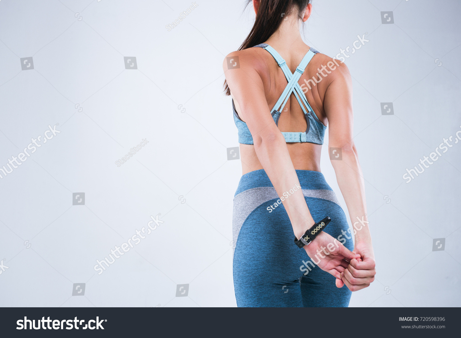 Back of beautiful fitness woman. Fitness girl do sport exercises isolated over gray background #720598396