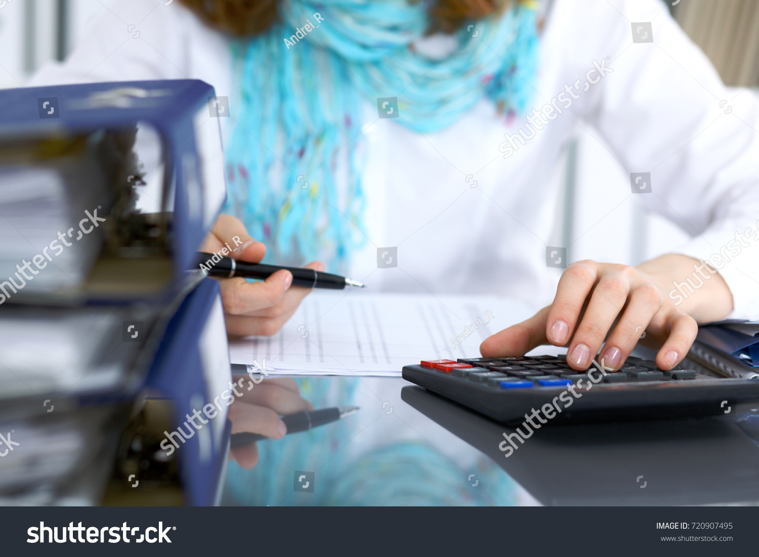 Female bookkeeper or financial inspector  making report, calculating or checking balance. Internal Revenue Service checking financial document. Audit concept #720907495
