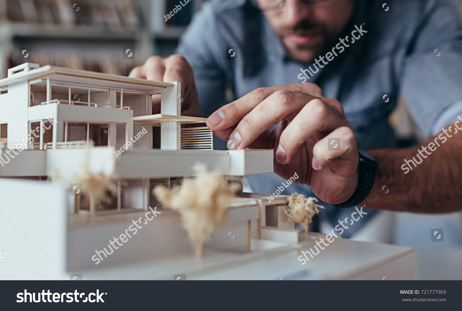 Close up of male architect hands making model house. Man architect working in the office. #721777969