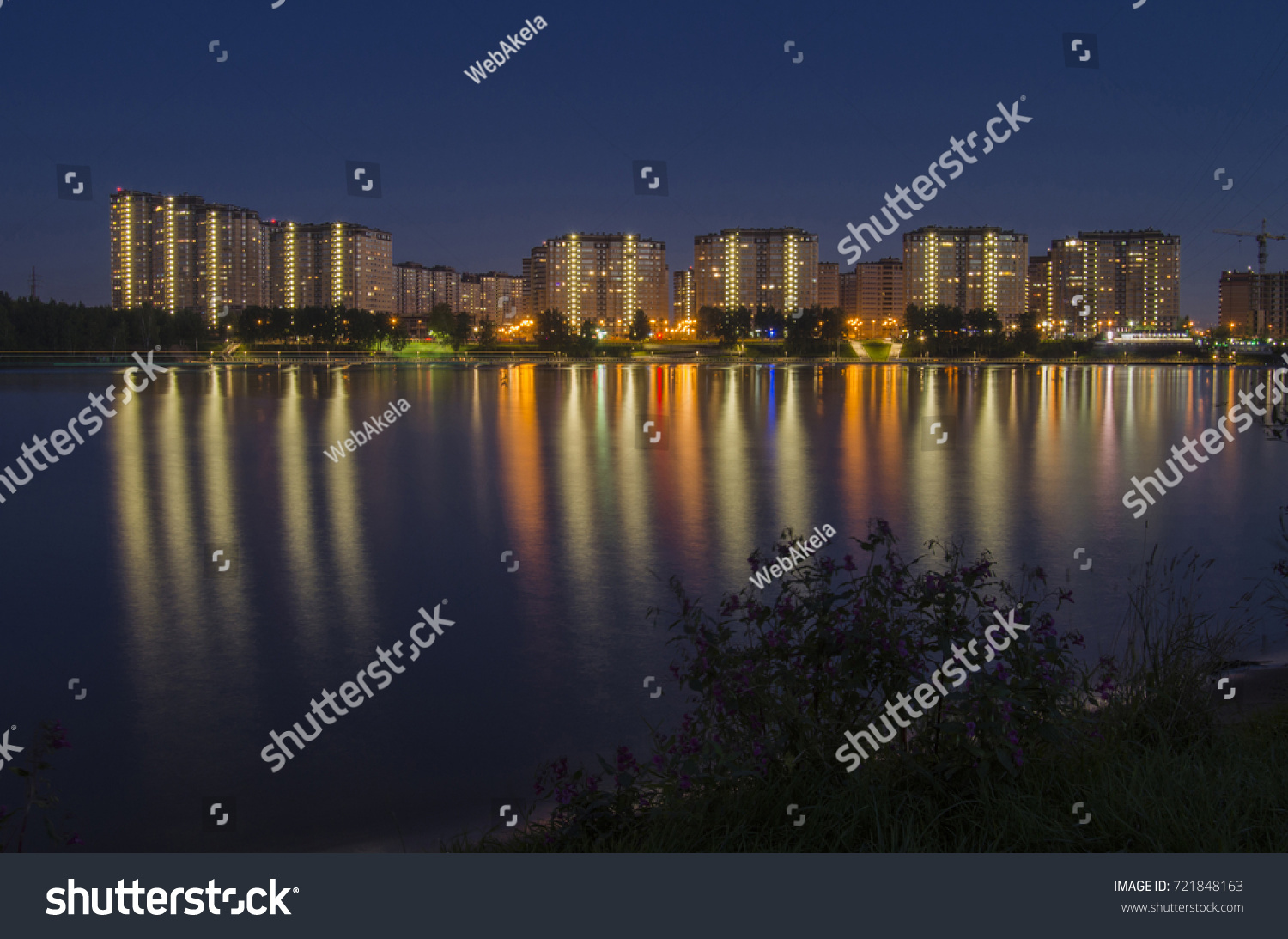 Residential complex of skyscrapers and the waterfront across the river reflected in the water. Night cityscape #721848163